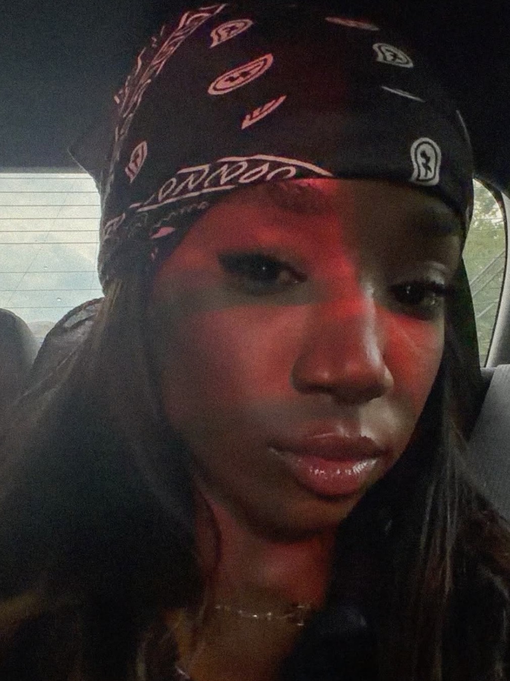 Close-up portrait of ADOREMIE in a bandana, lit red